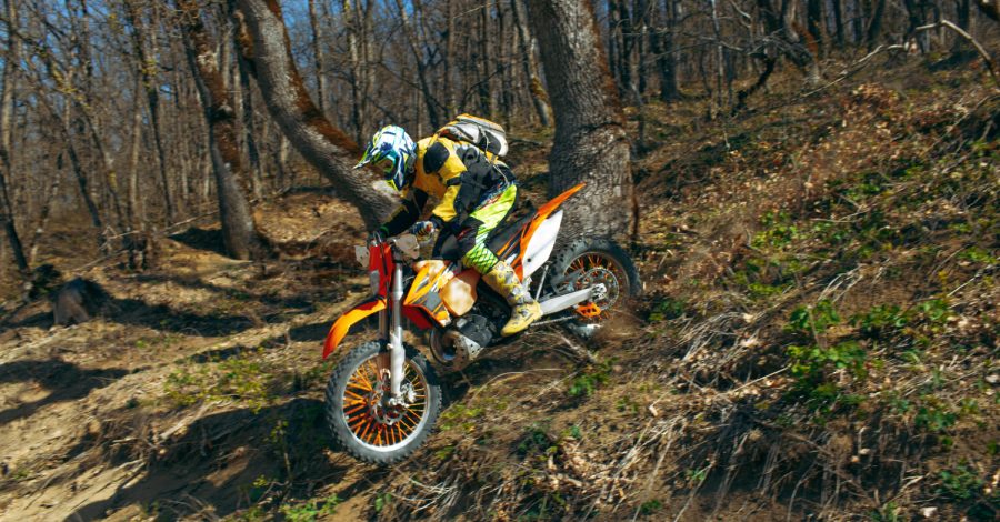 Imagem ilustrando o conteúdo sobre como se preparar para uma corrida de motocross mostrando um competidor correndo em uma área de mata.