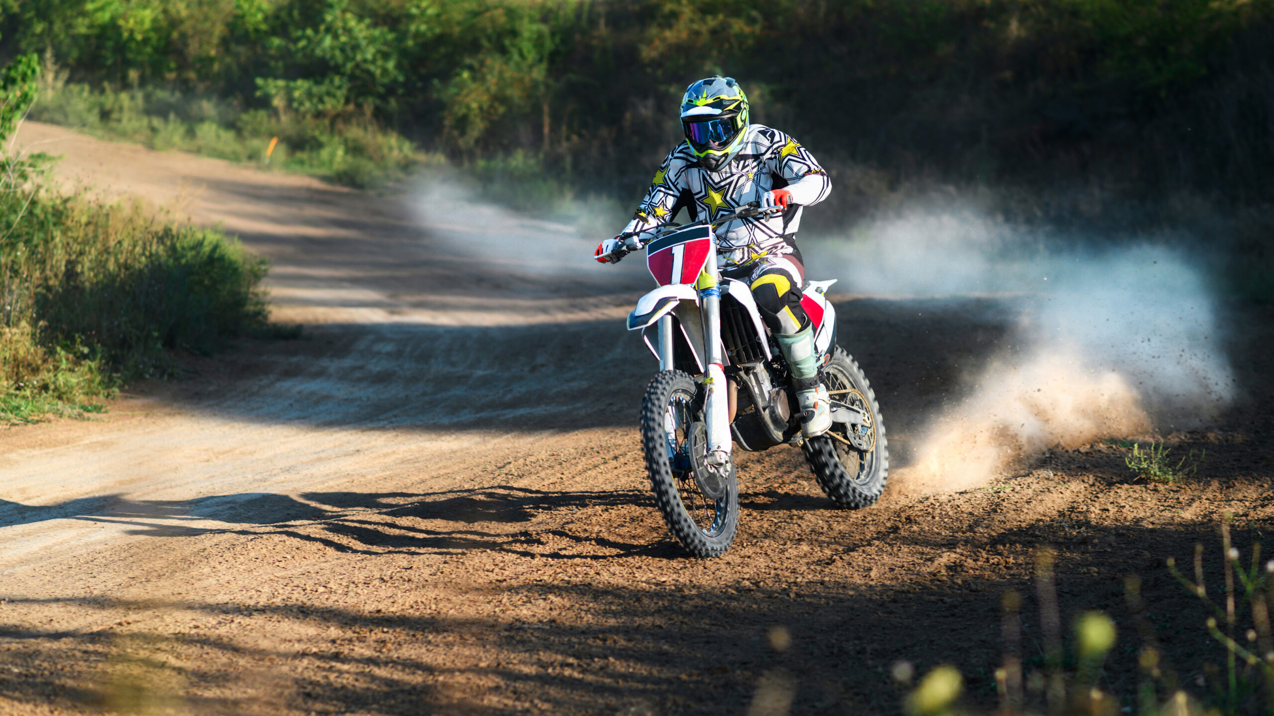 Imagem ilustrando o conteúdo sobre como planejar uma trilha de motocross mostrando um piloto em uma trilha cercada por amta em um dia ensolarado.